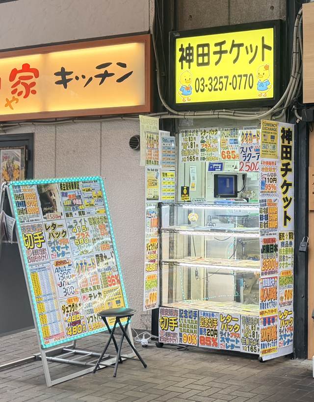 神田チケットの店頭。ガード下のガラスケース型店舗と価格表